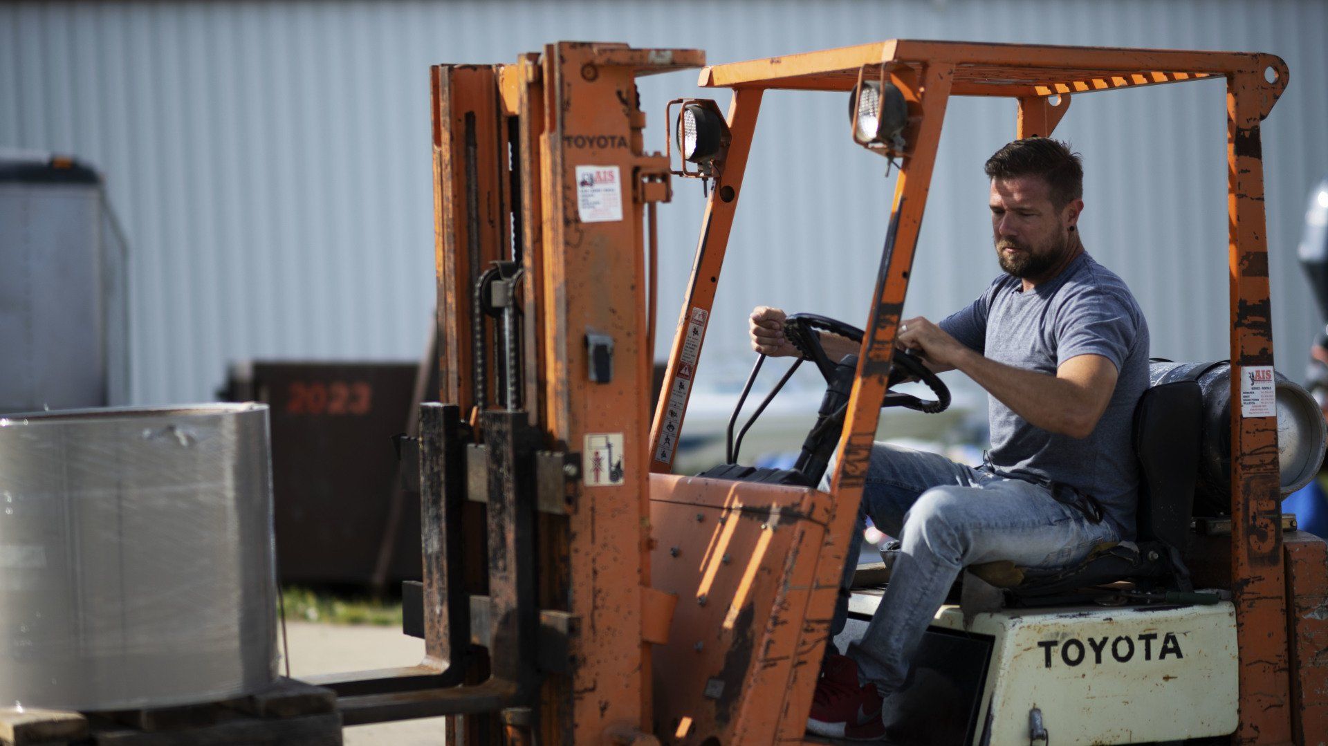 a man is driving a toyota forklift in a parking lot .