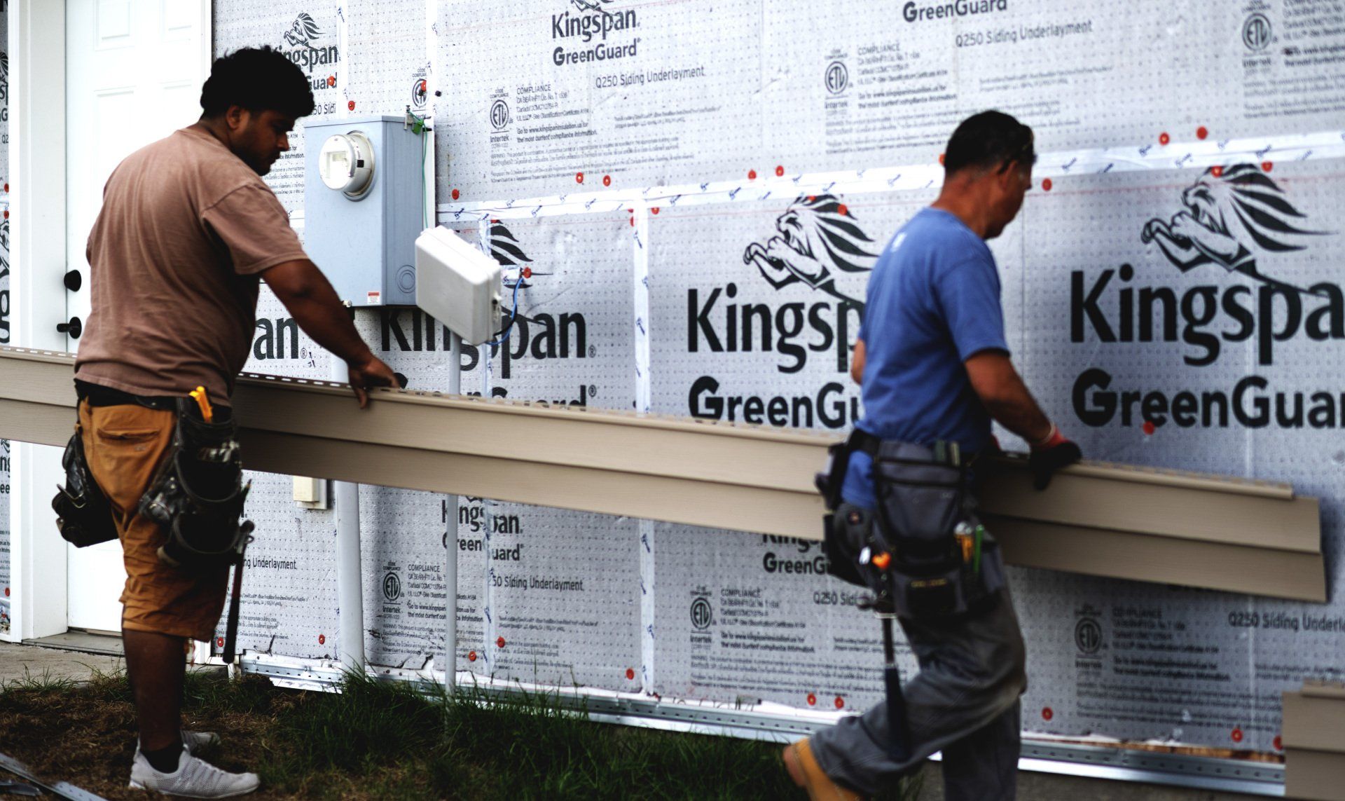 two men are working on a kingspan greenguard wall