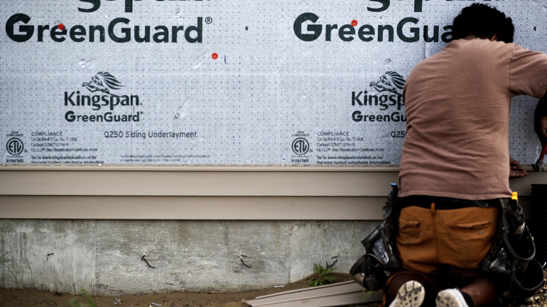 a man is kneeling down in front of a greenguard wall .