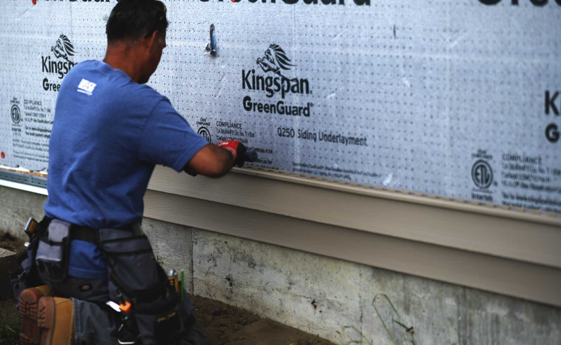 a man is installing siding on the side of a house .