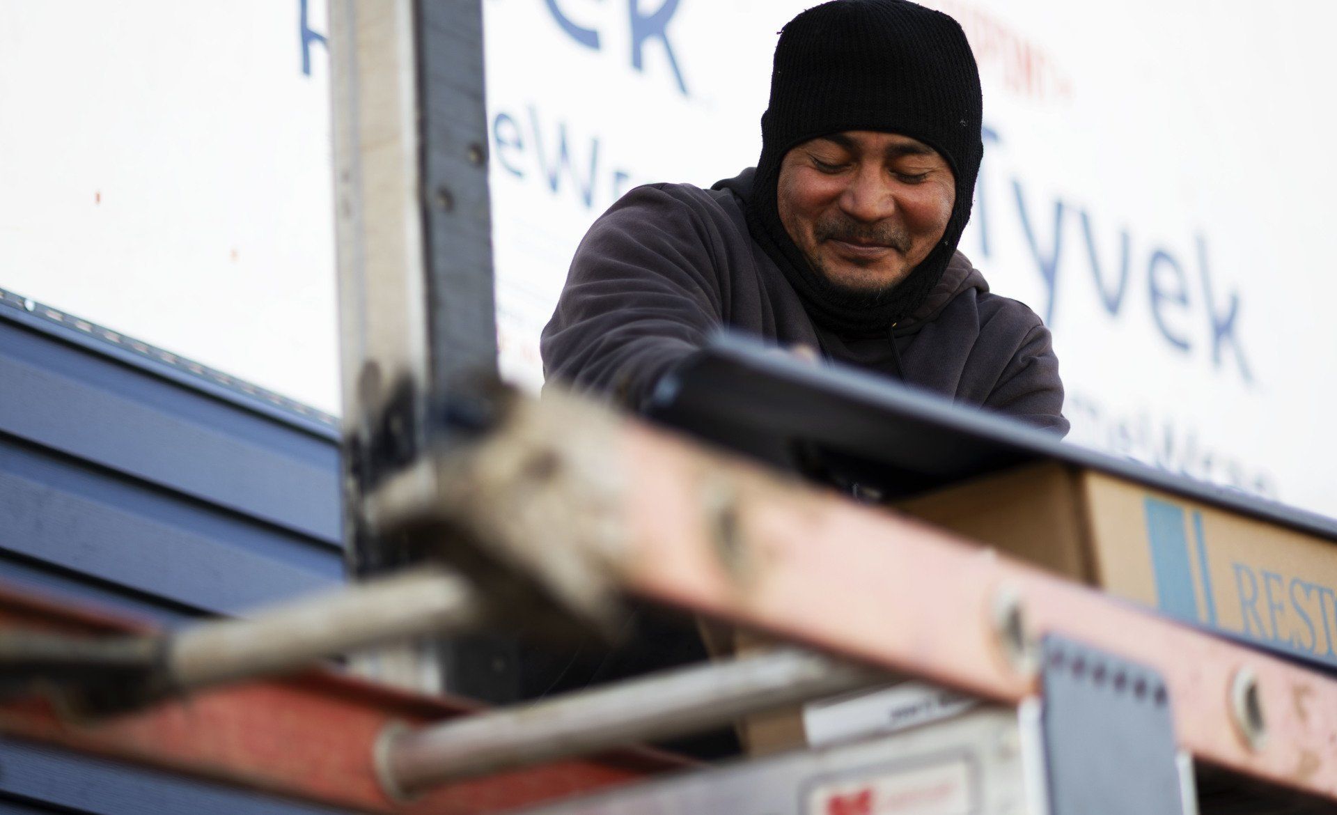 a man standing on a ladder in front of a sign that says vyvek