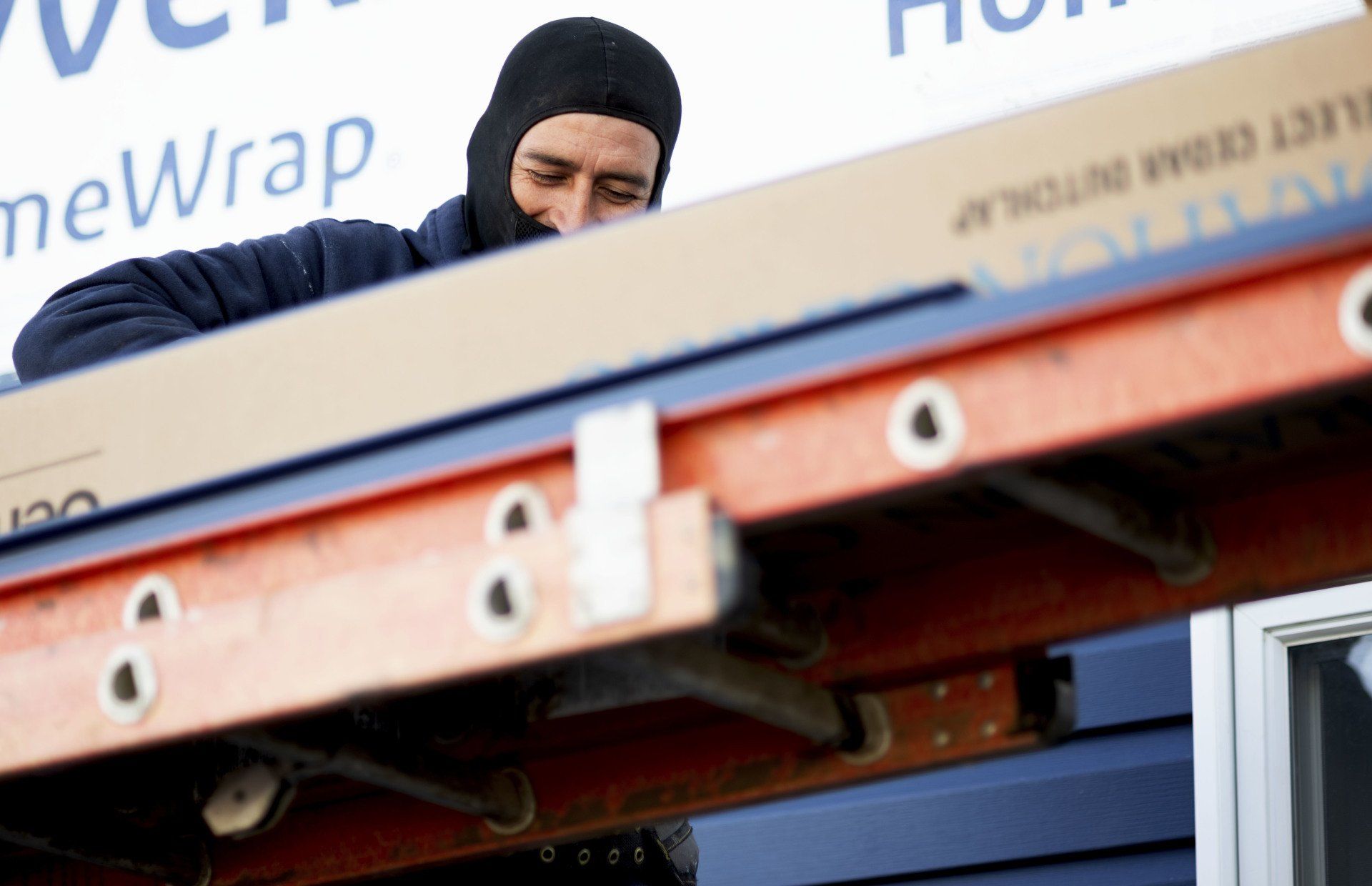 a man wearing a mask is standing on a ladder with a box in the background that says newwrap