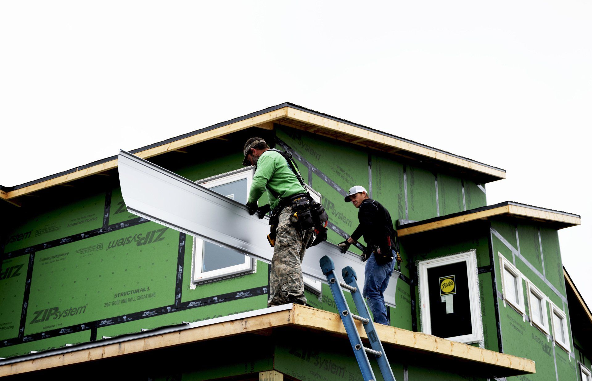 two men are working on the roof of a house .