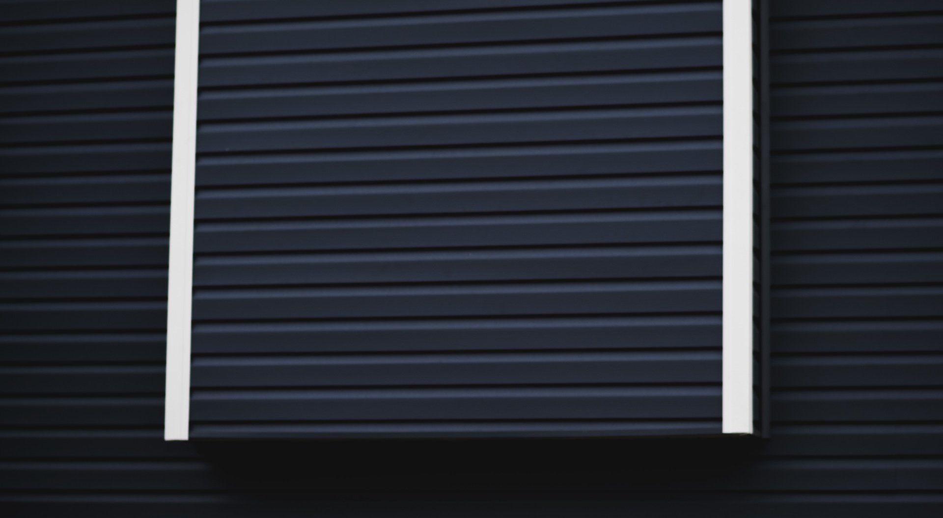 a close up of a black siding on a house with a white trim .