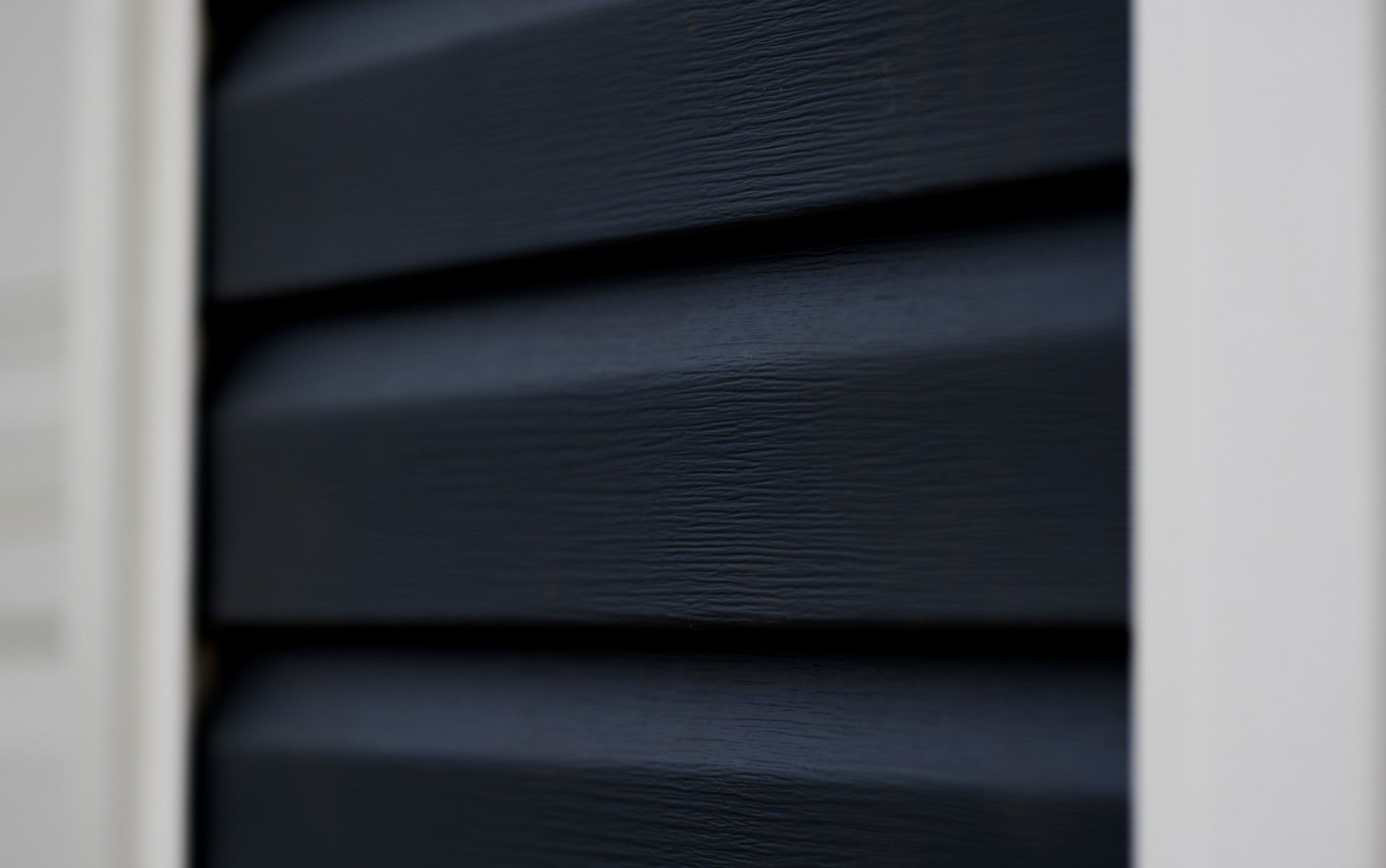 a close up of a black siding on a house with a white trim .