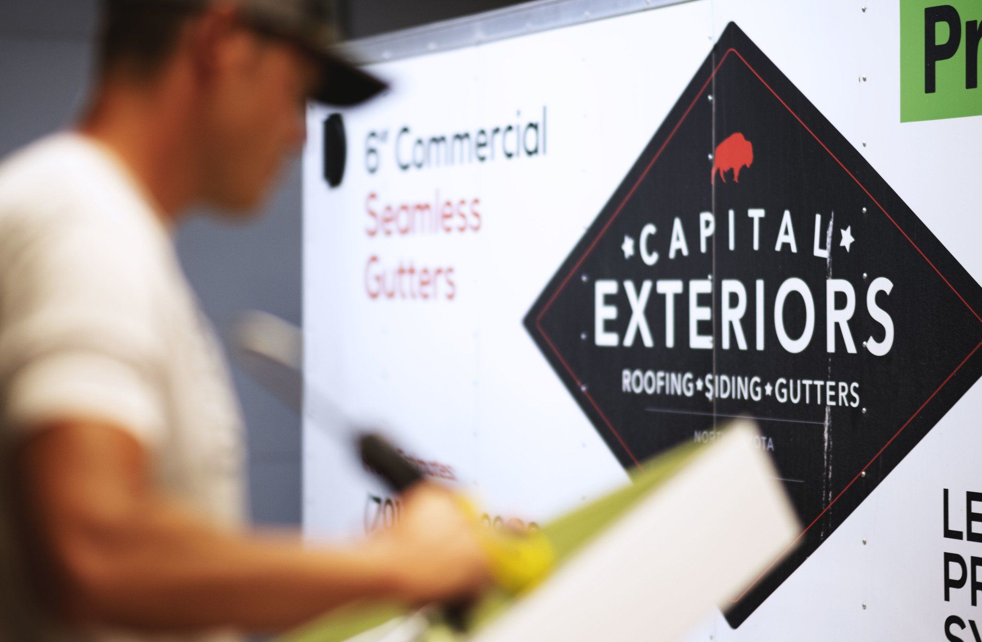a man standing in front of a sign that says capital exteriors