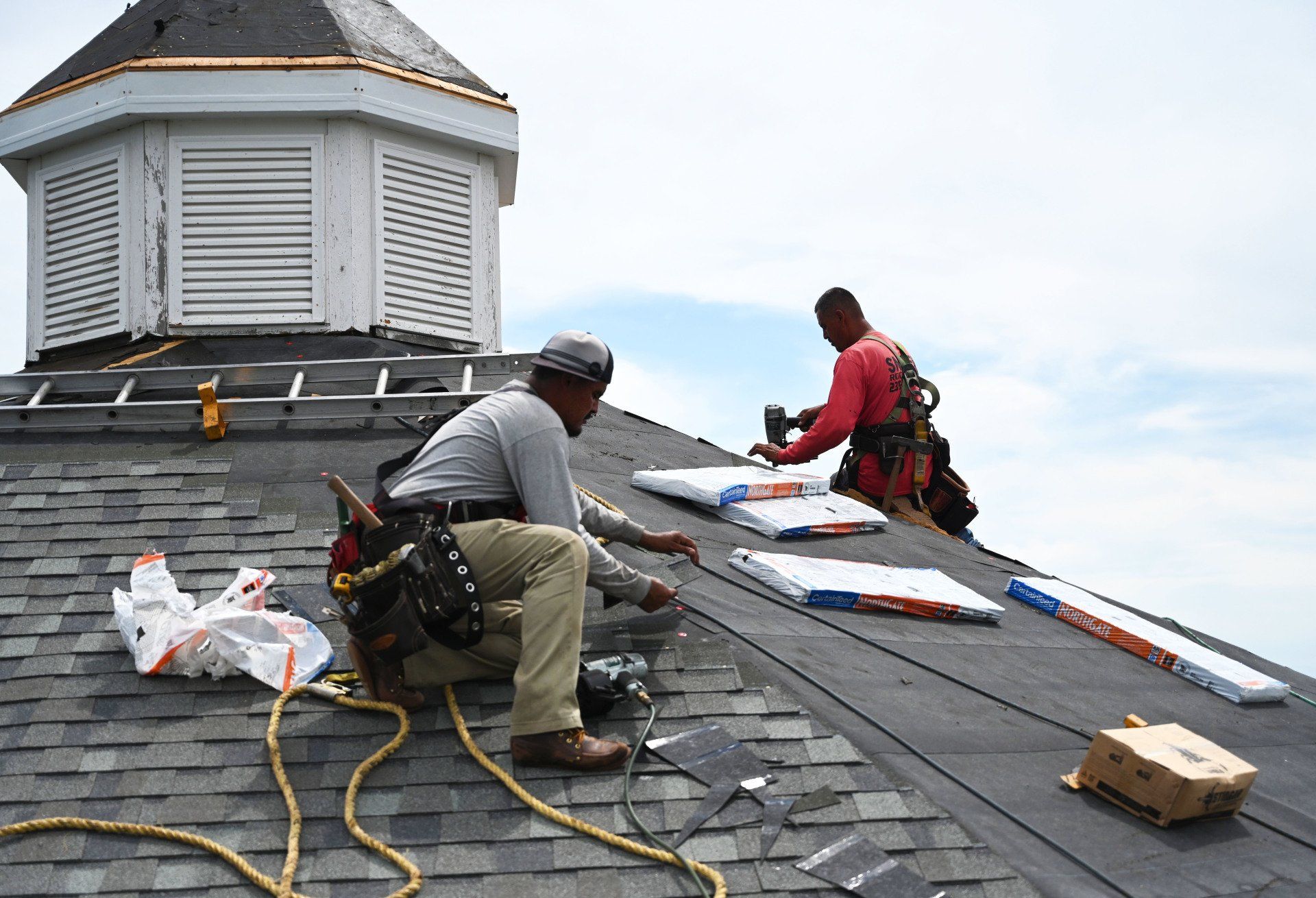 two men are working on the roof of a building .