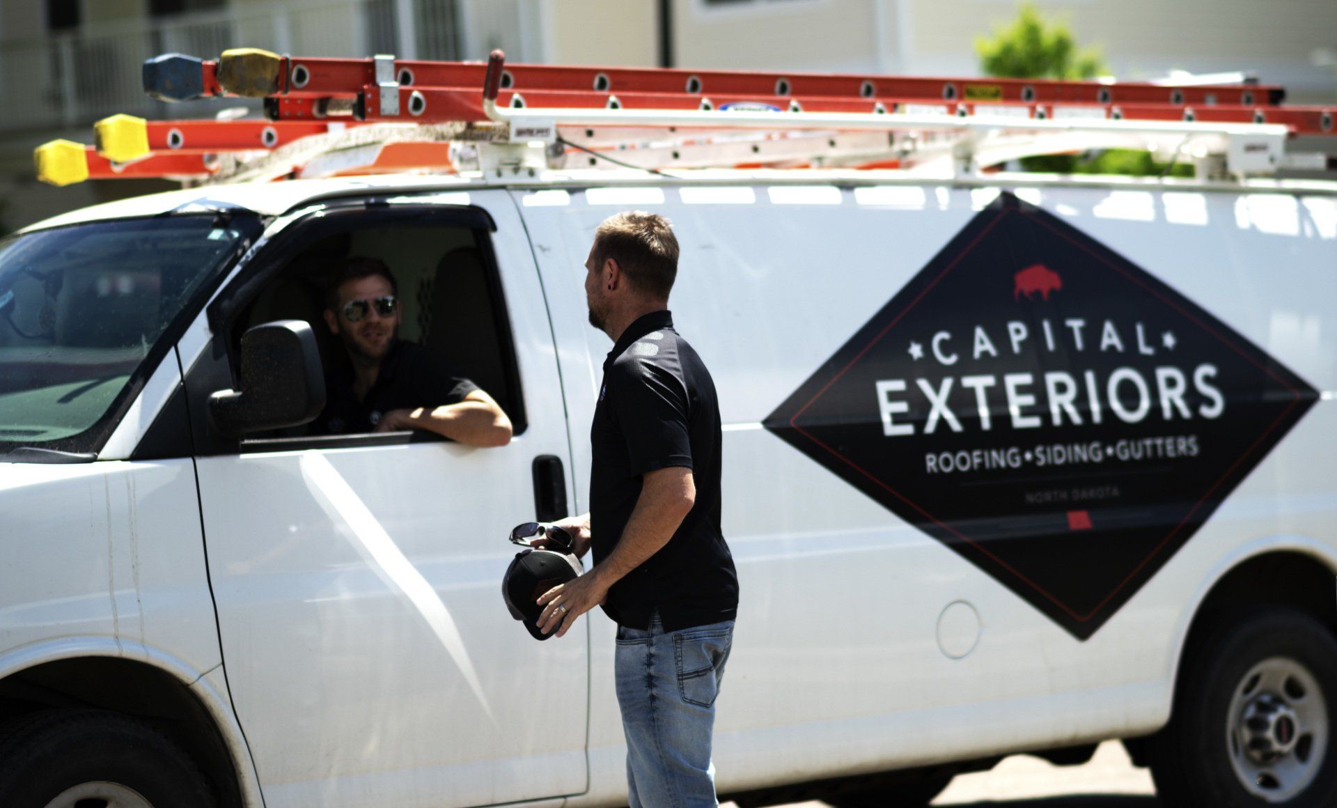 a man standing next to a van that says capital exteriors