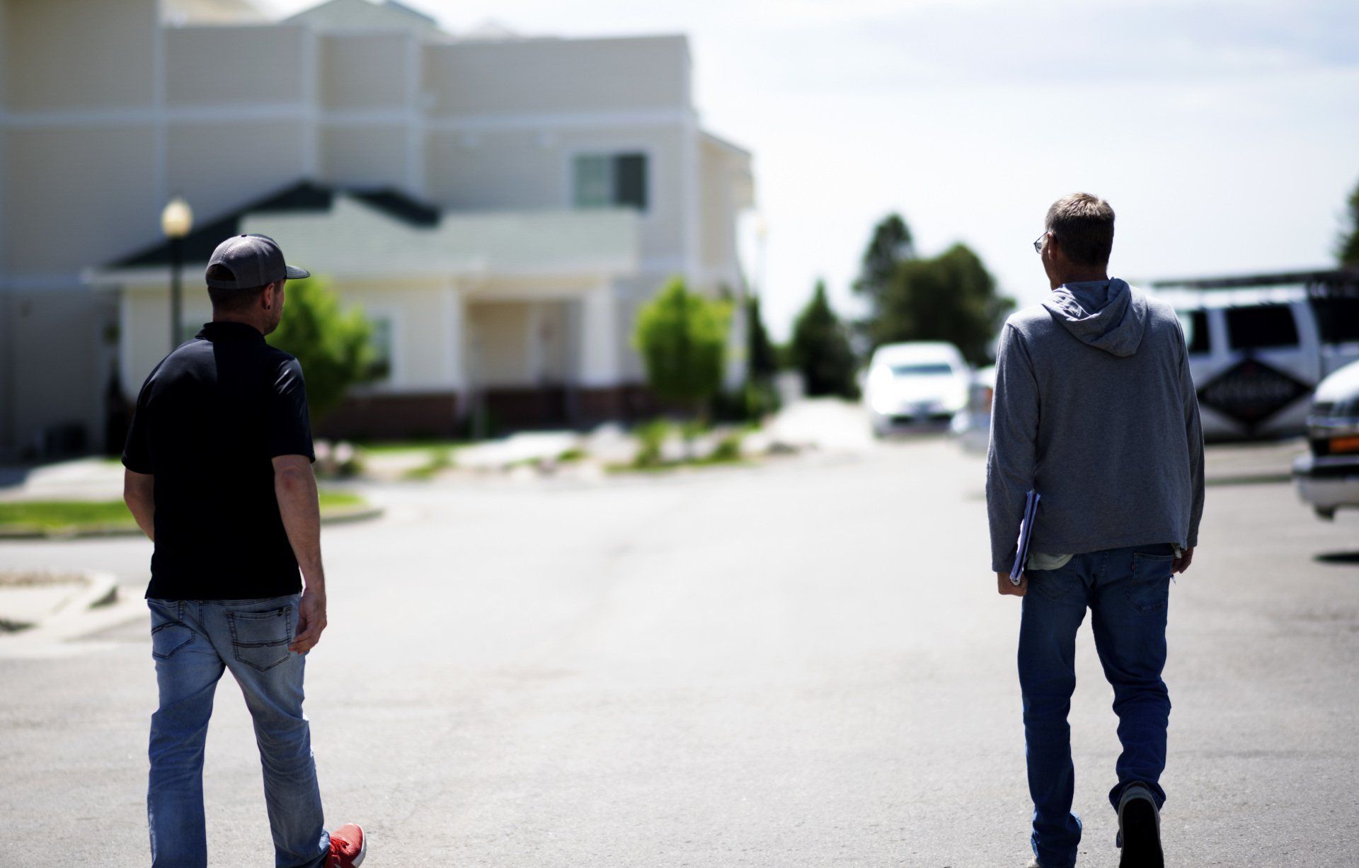 two men standing next to each other on a street in front of a house .