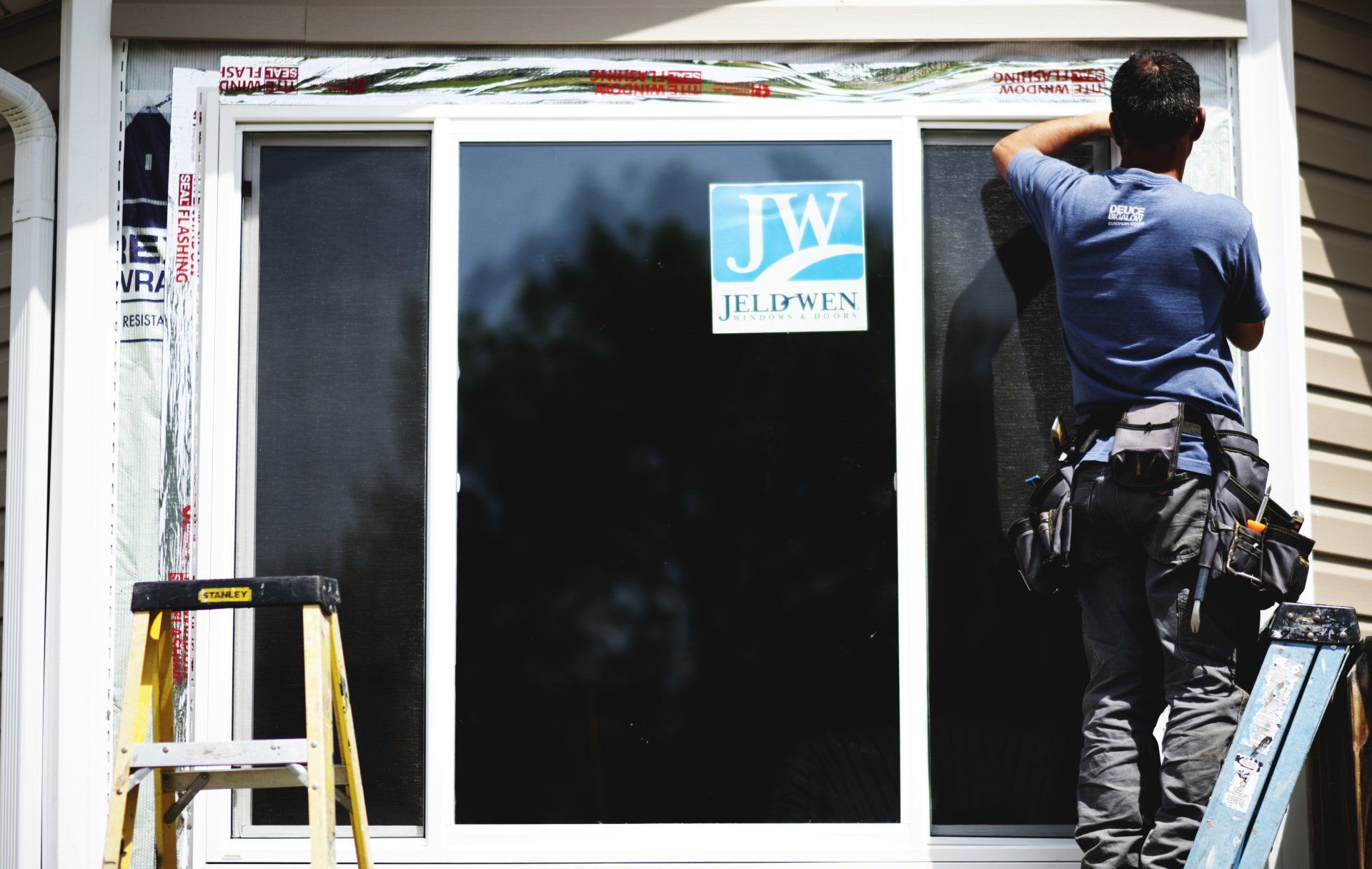 a man is installing a window with a jw sticker on it