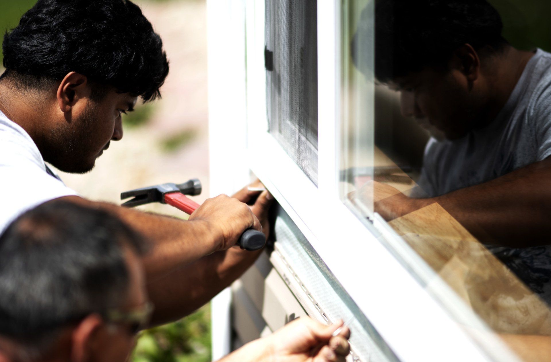 a man is working on a window with a hammer