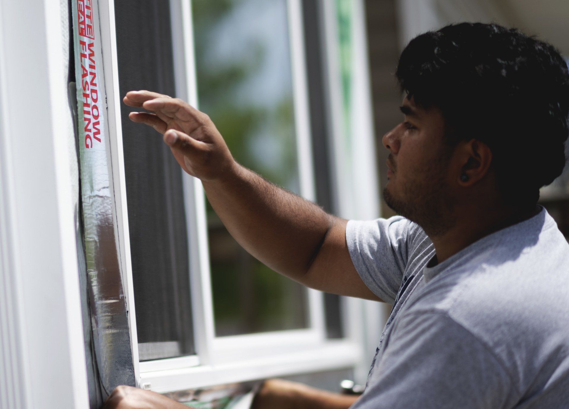 a man is working on a window with a piece of tape that says window flashing