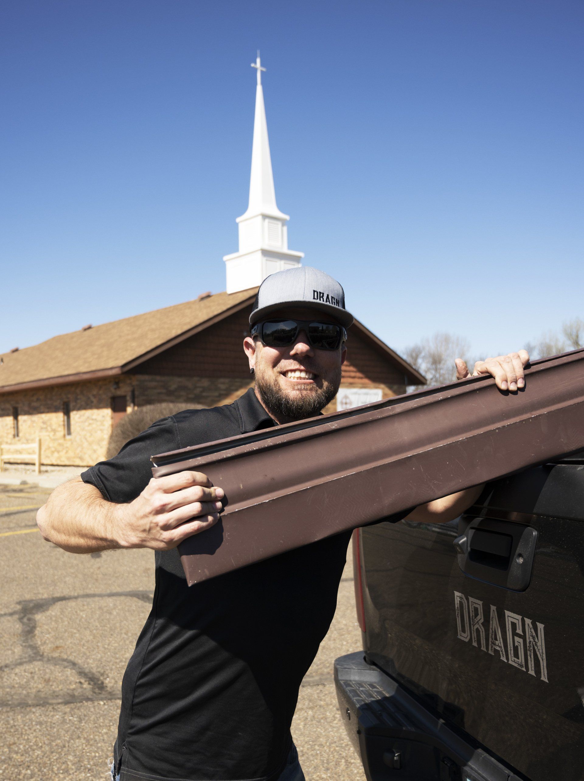 a man is holding a piece of metal in front of a church .
