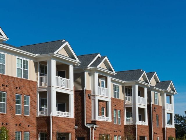 A large apartment building with a blue sky in the background