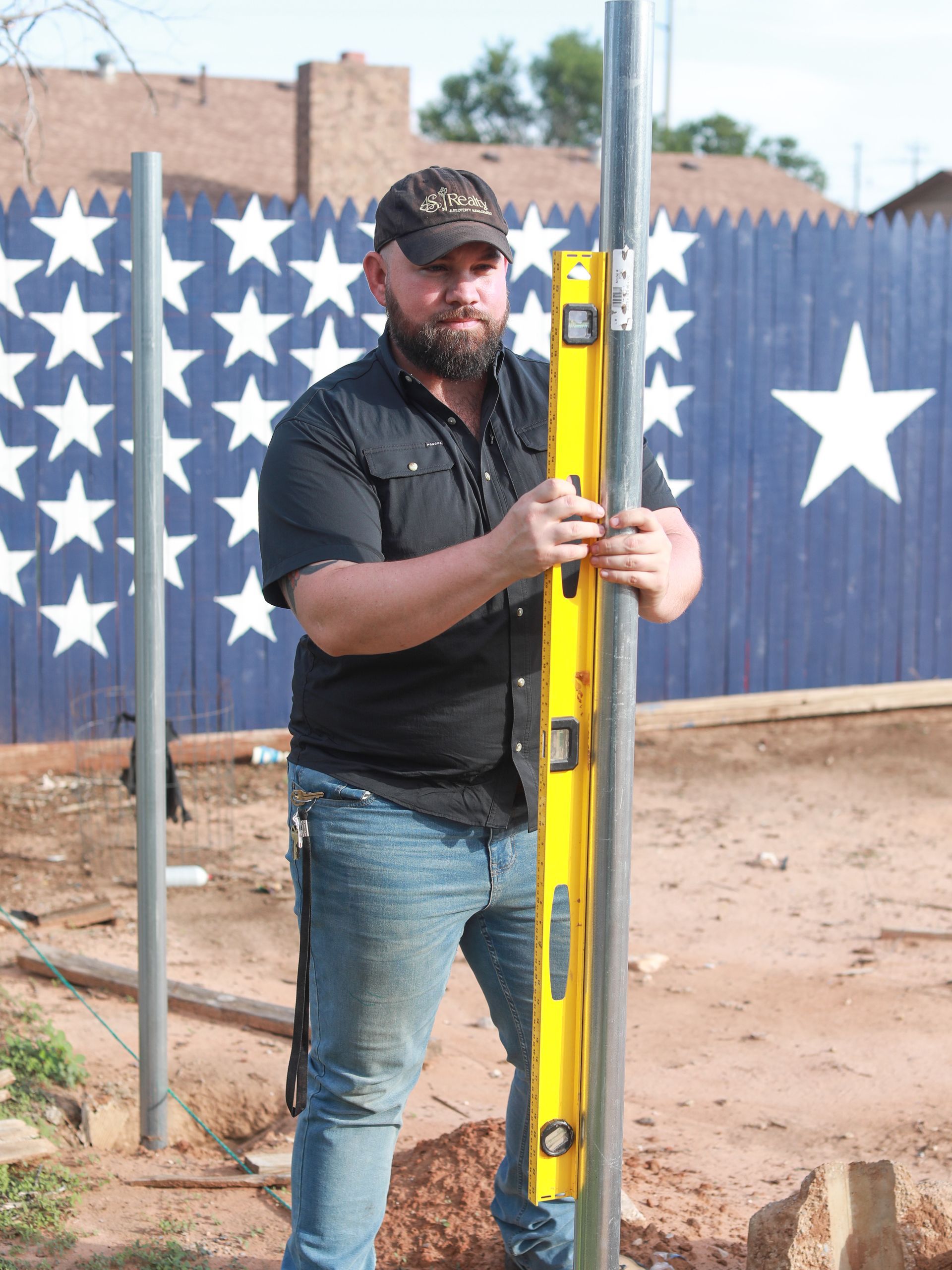 A man is holding a yellow level in front of an american flag