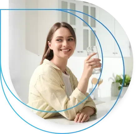 Woman smiling, holding a glass of water in a kitchen. Woman smiling, holding a glass of water in a kitchen.
