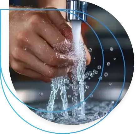 A hand under running water from a faucet, splashing into a sink. A hand under running water from a faucet, splashing into a sink.