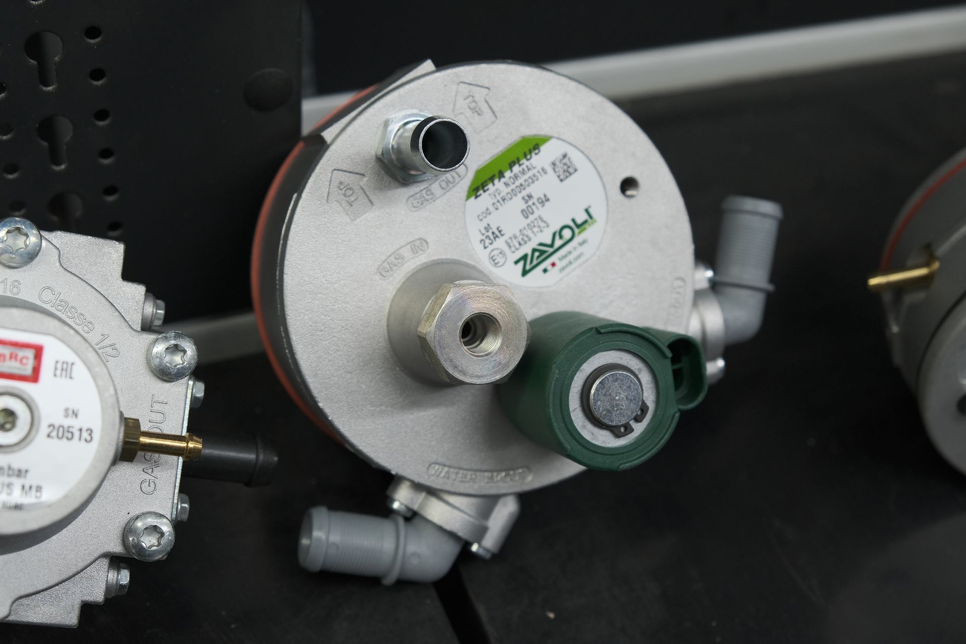 Primo piano di un regolatore del gas Zavoli argentato con dettagli verdi e varie porte.