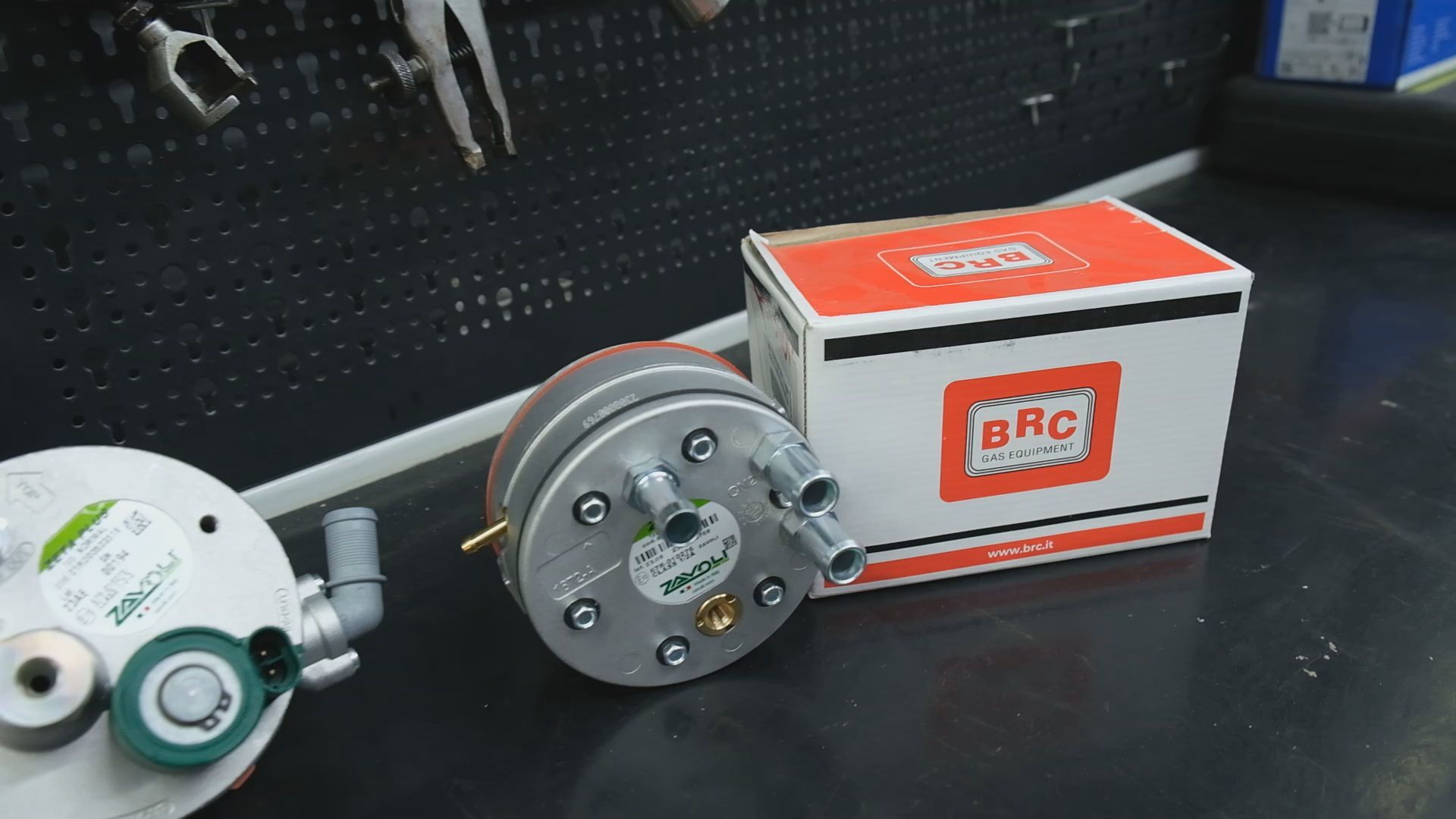 Un convertitore di gas BRC, una scatola e i relativi componenti su una superficie di lavoro.