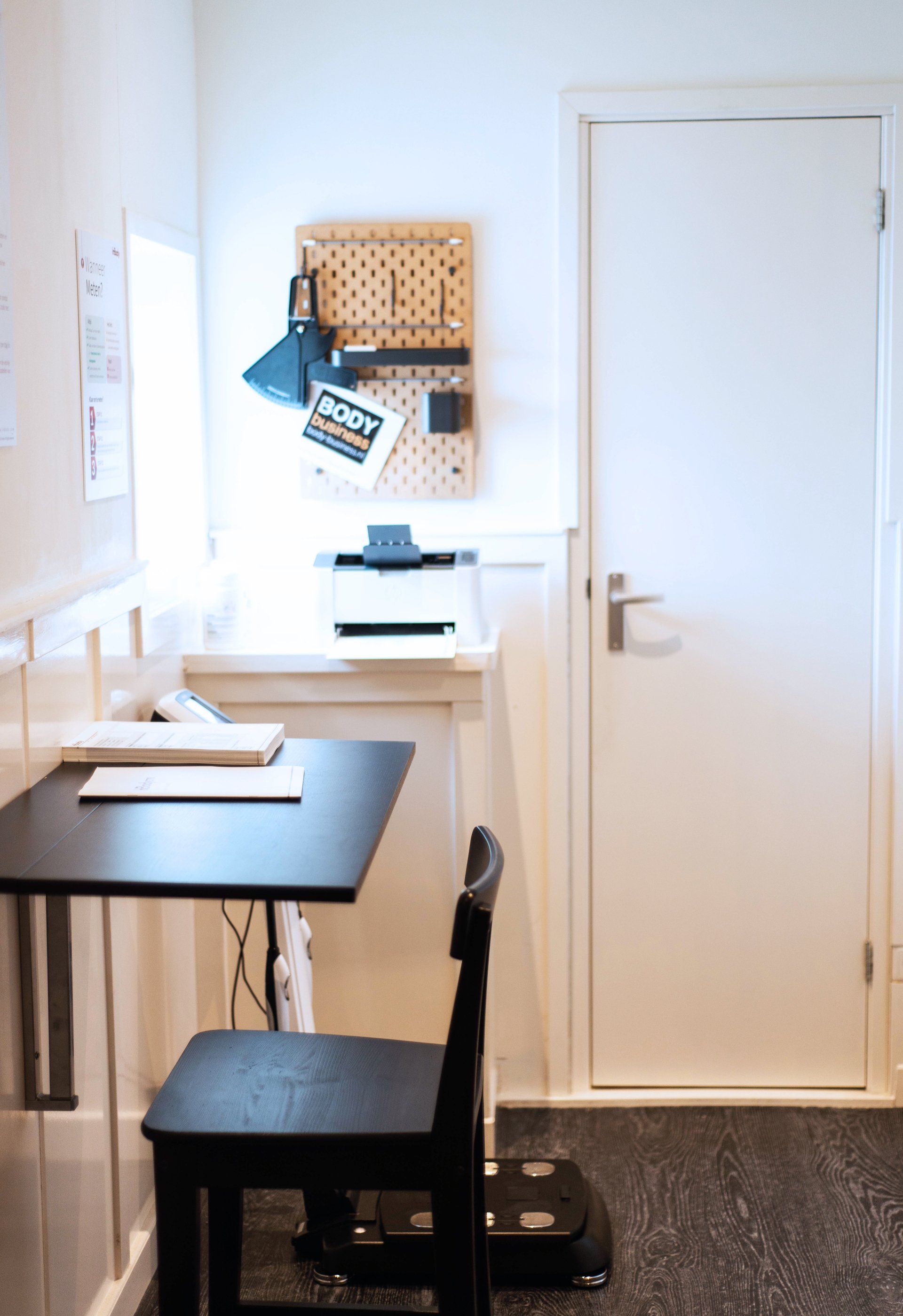 een klein bureau met een stoel in een kamer naast een deur.