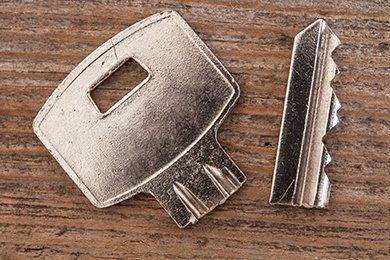 broken silver key on wood grained background