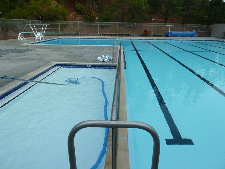 Swimming pools with blue water and diving board; exterior shot.