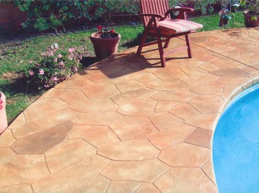 Stamped concrete patio with a stone pattern next to a pool and a chair. Stamped concrete patio with a stone pattern next to a pool and a chair.