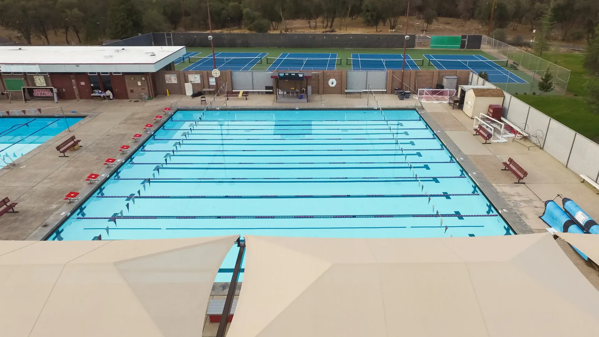 An aerial view of a large outdoor swimming pool with lanes, adjacent to a smaller pool.