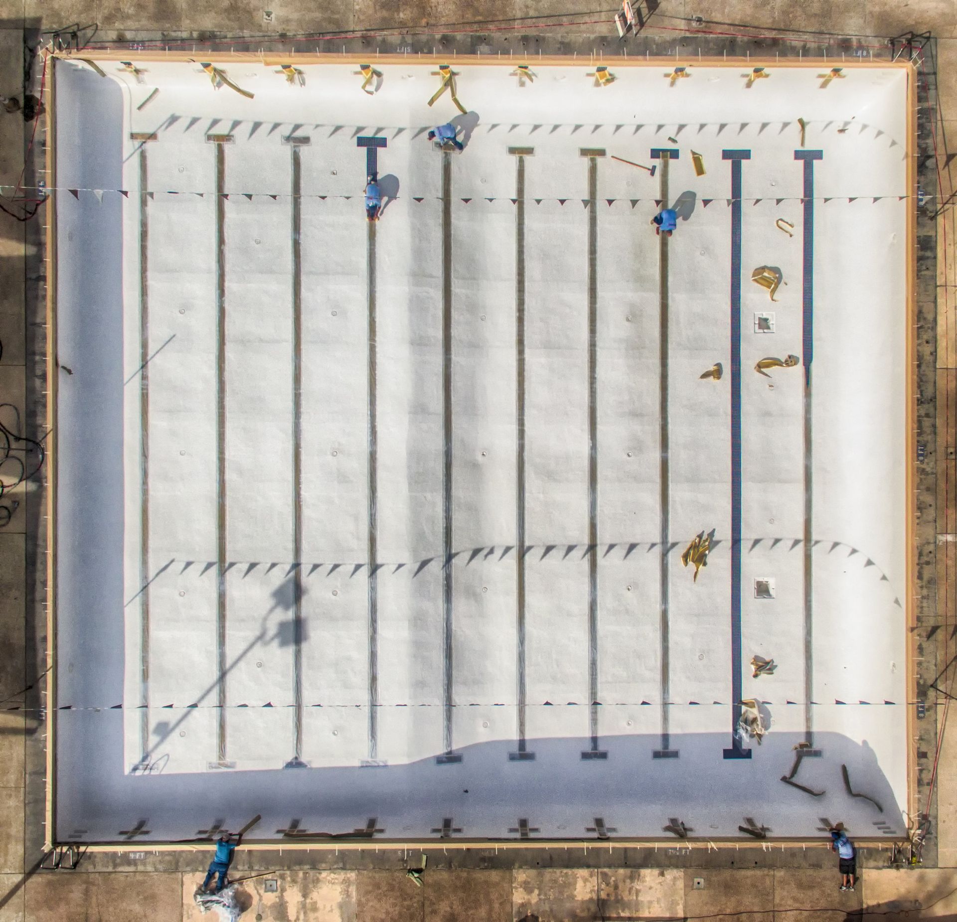 Aerial view of an empty swimming pool under construction; workers are present.