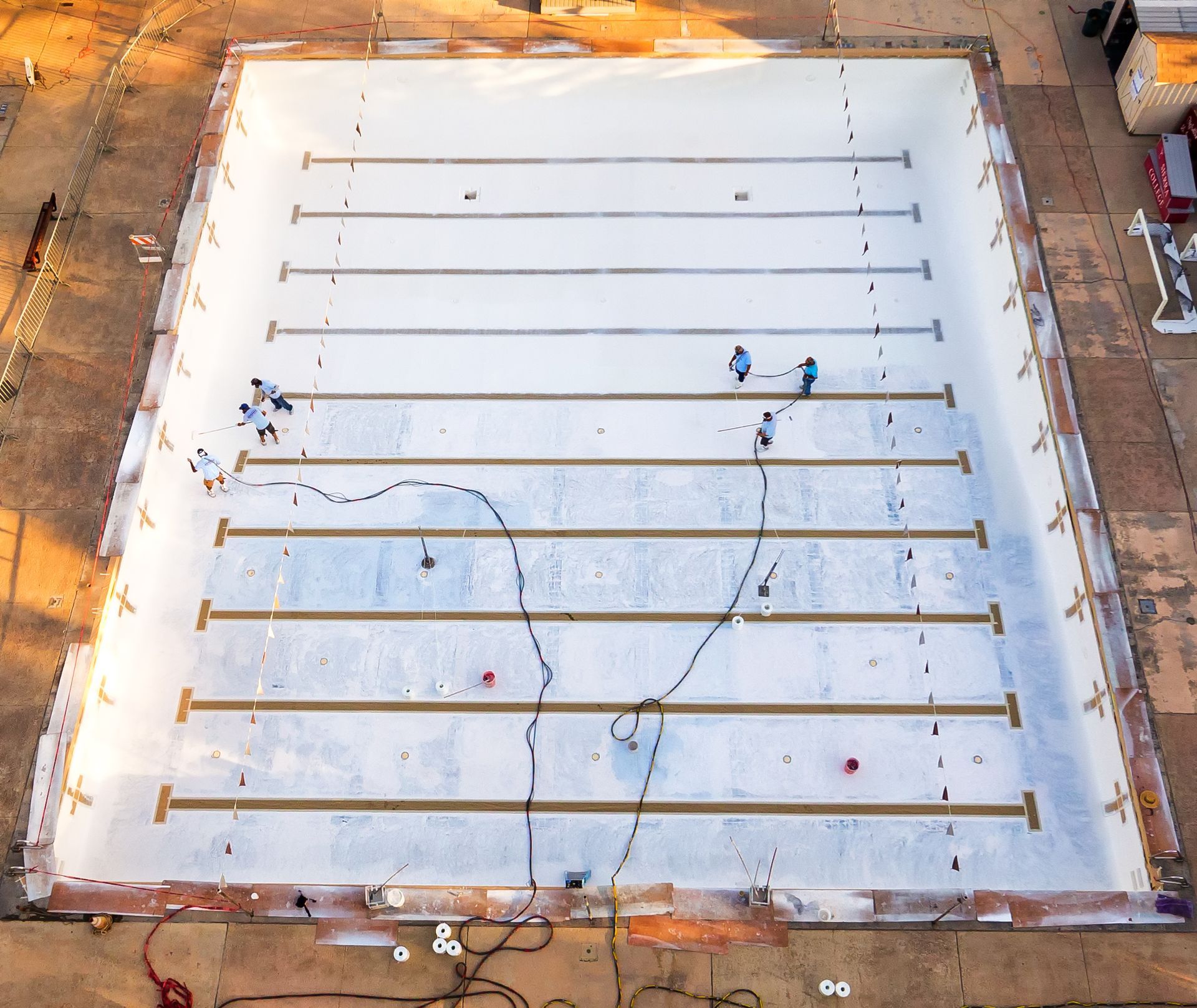 Overhead view of a rectangular pool under construction with workers inside laying down materials.