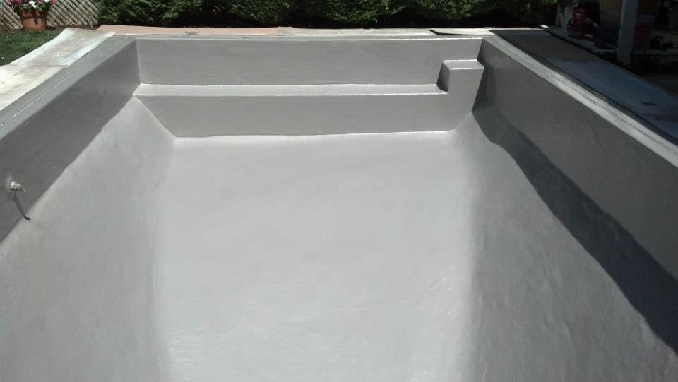 Empty, gray rectangular pool with built-in steps and coping.