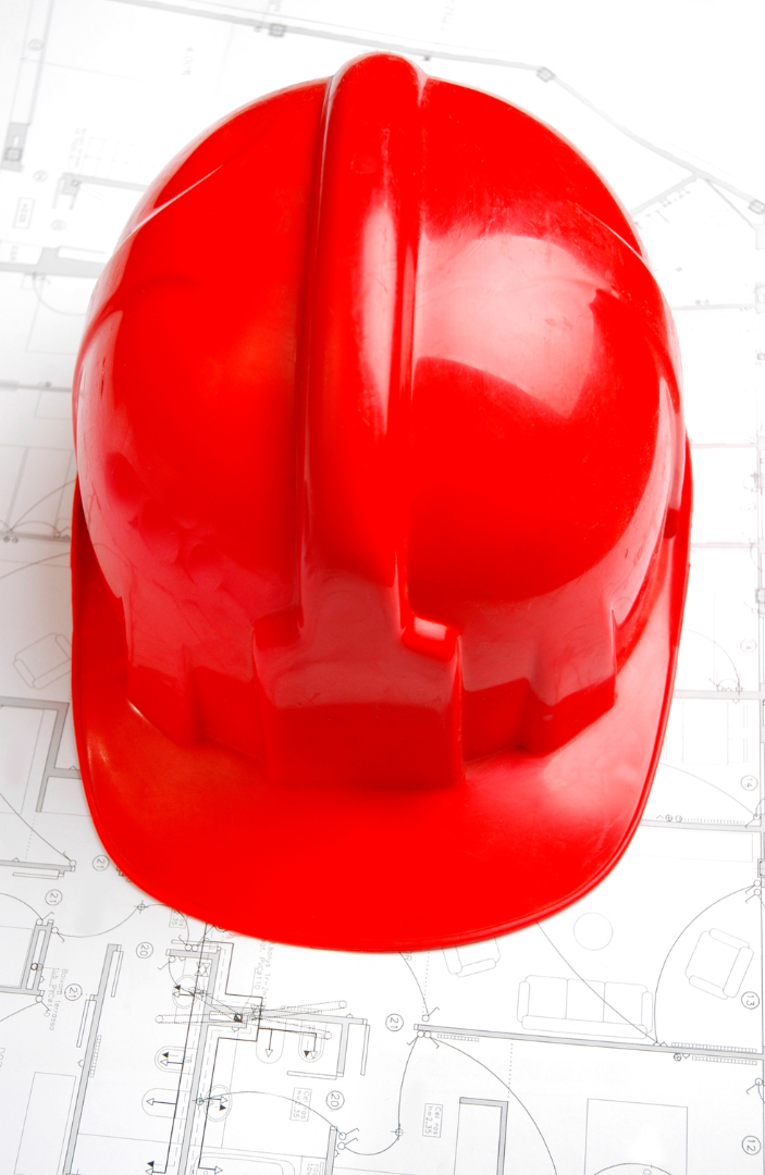 A red hard hat is sitting on top of a blueprint.