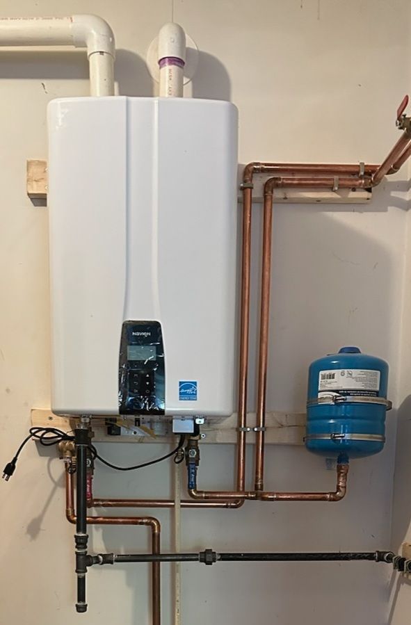 White tankless water heater on a wall with copper pipes and a blue expansion tank.