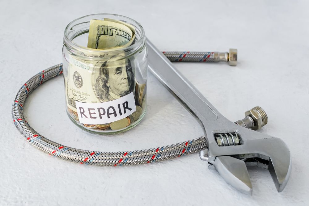 A jar filled with money and a wrench next to a hose.