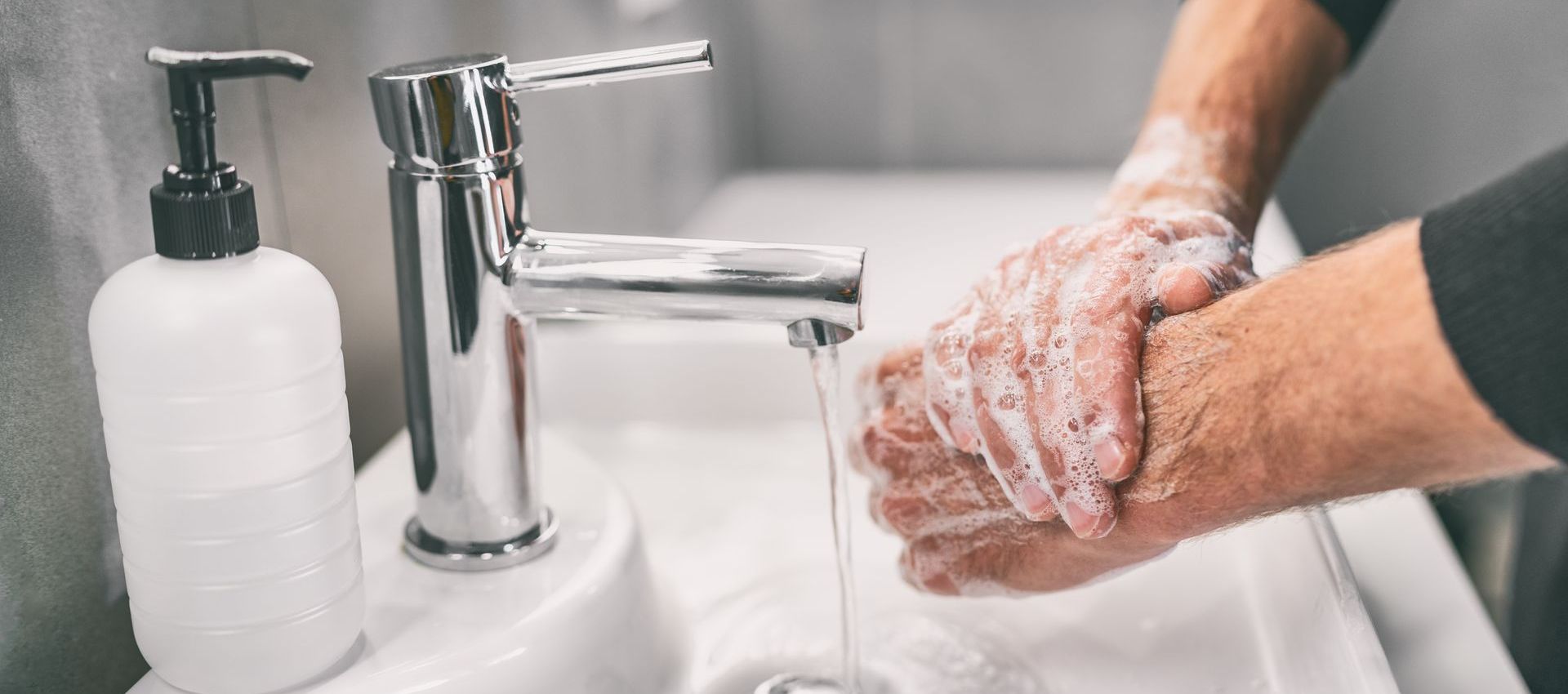 A person is washing their hands in a bathroom sink.