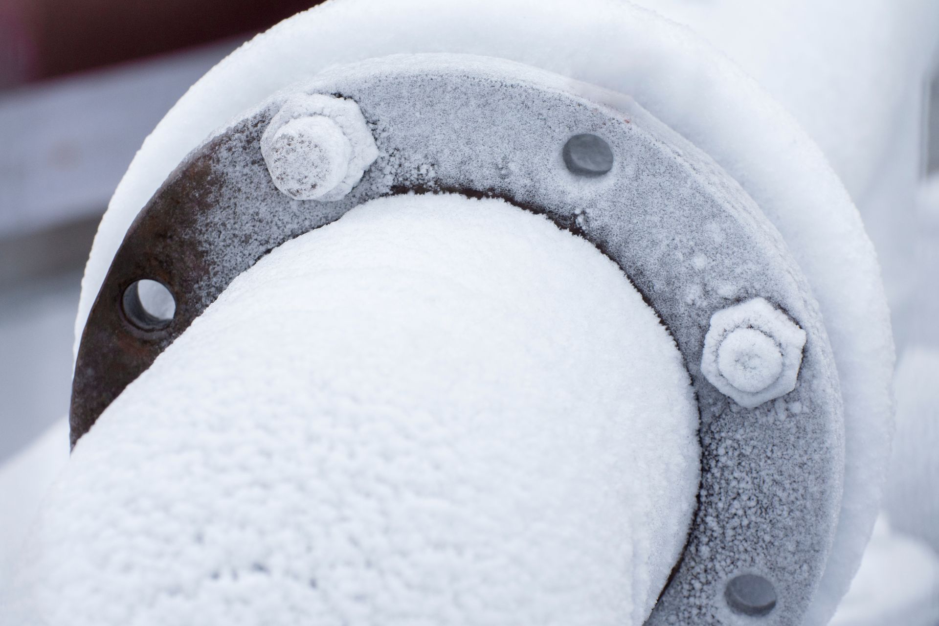 Frost-covered pipe and flange with bolts, outdoor, cold environment.