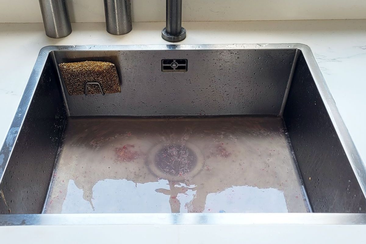 A kitchen sink with a stainless steel faucet and soap dispensers