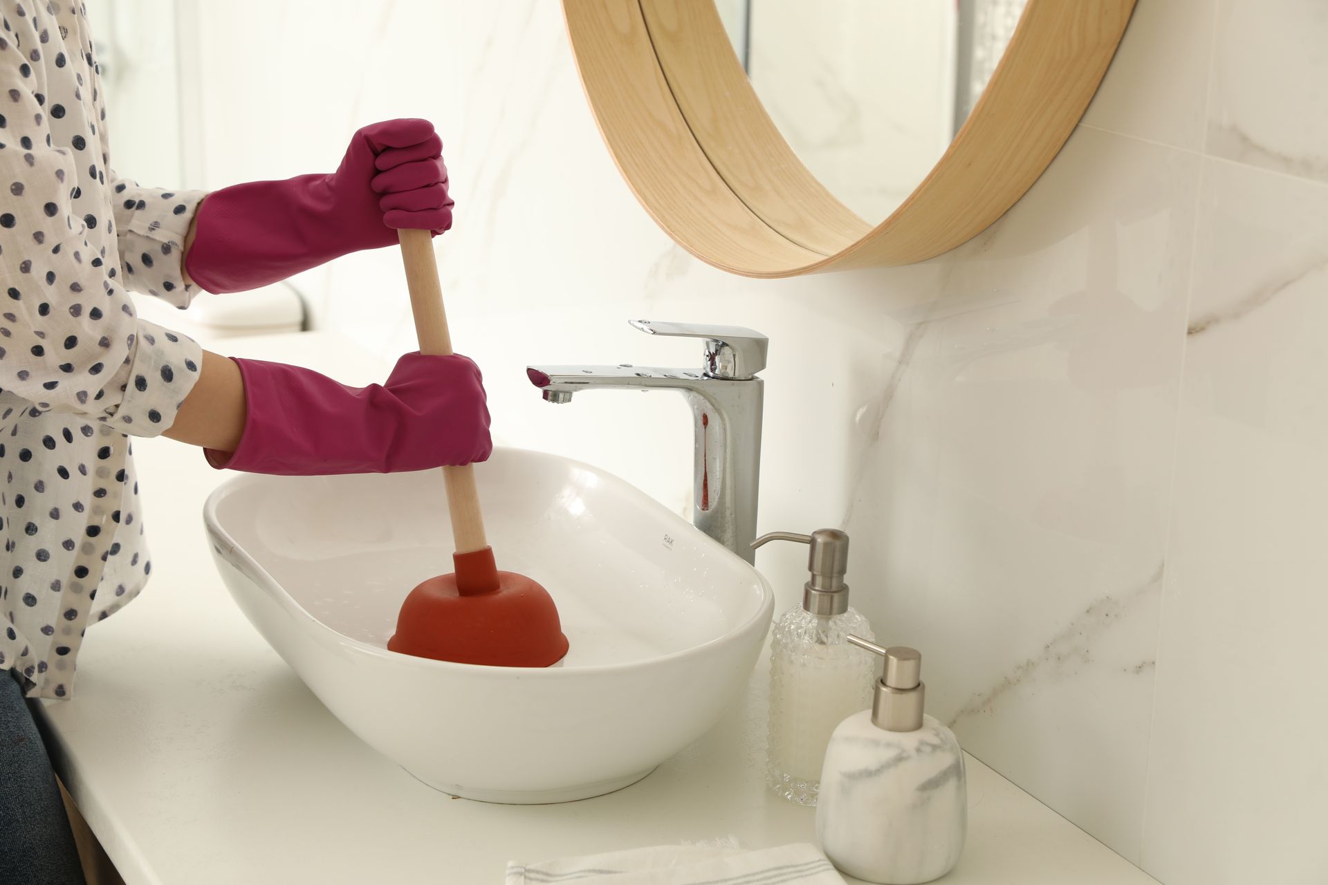 A woman is using a plunger in a bathroom sink.