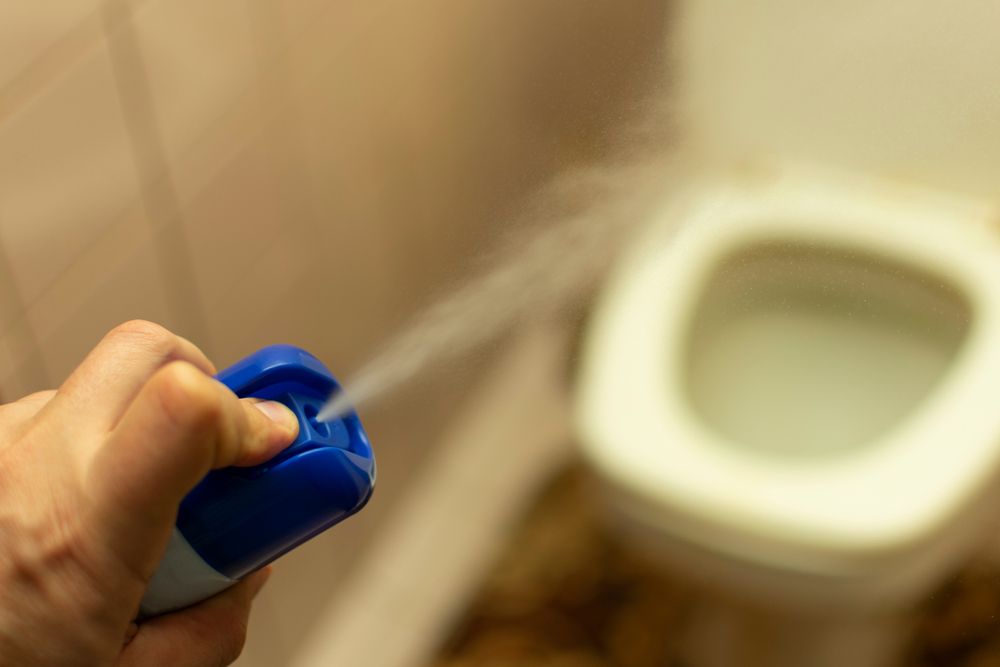 A person is spraying a toilet with a spray bottle.