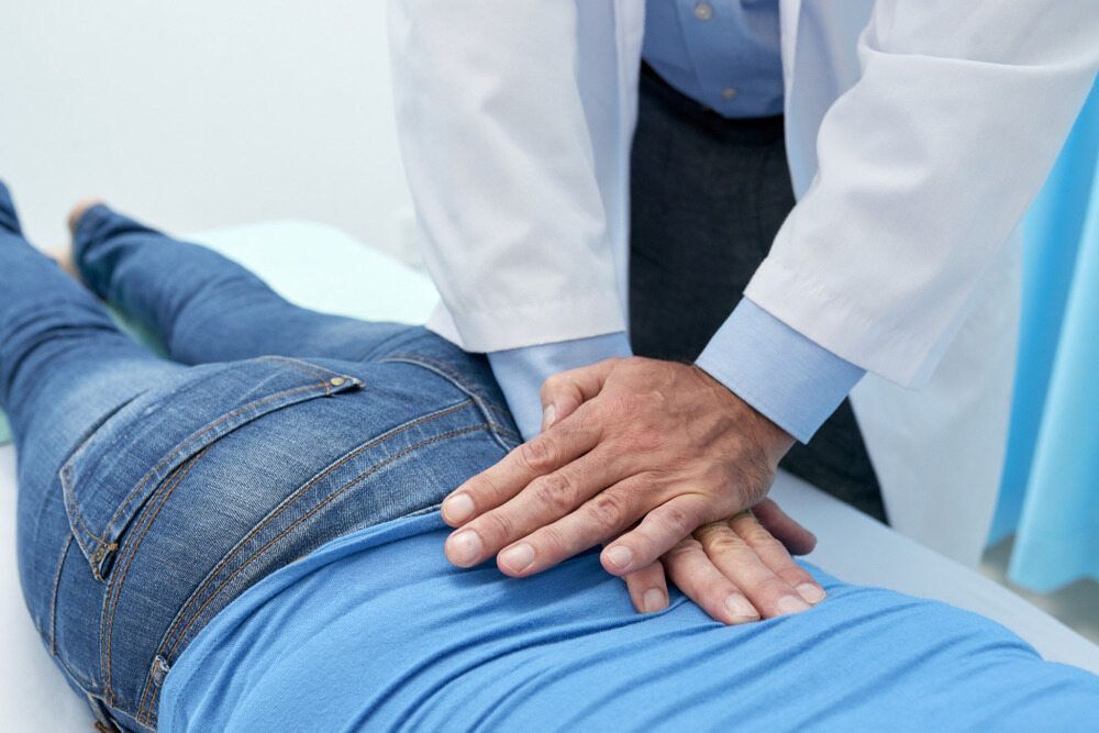 A Doctor is Massaging a Patient 's Back With His Hands — Anderson Family Chiropractic Health Centre in Mount Pleasant, QLD