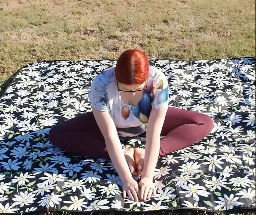 A Woman is Stretching on a Blanket With Daisies on It — Anderson Family Chiropractic Health Centre in Mount Pleasant, QLD
