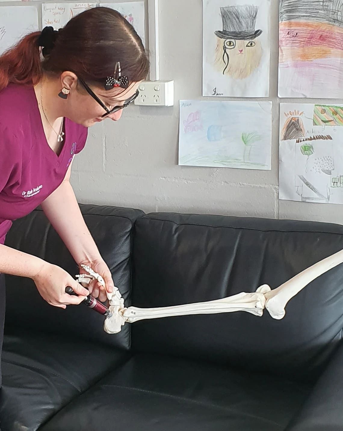 A Woman is Holding a Skeleton Leg on a Couch — Anderson Family Chiropractic Health Centre in Mount Pleasant, QLD