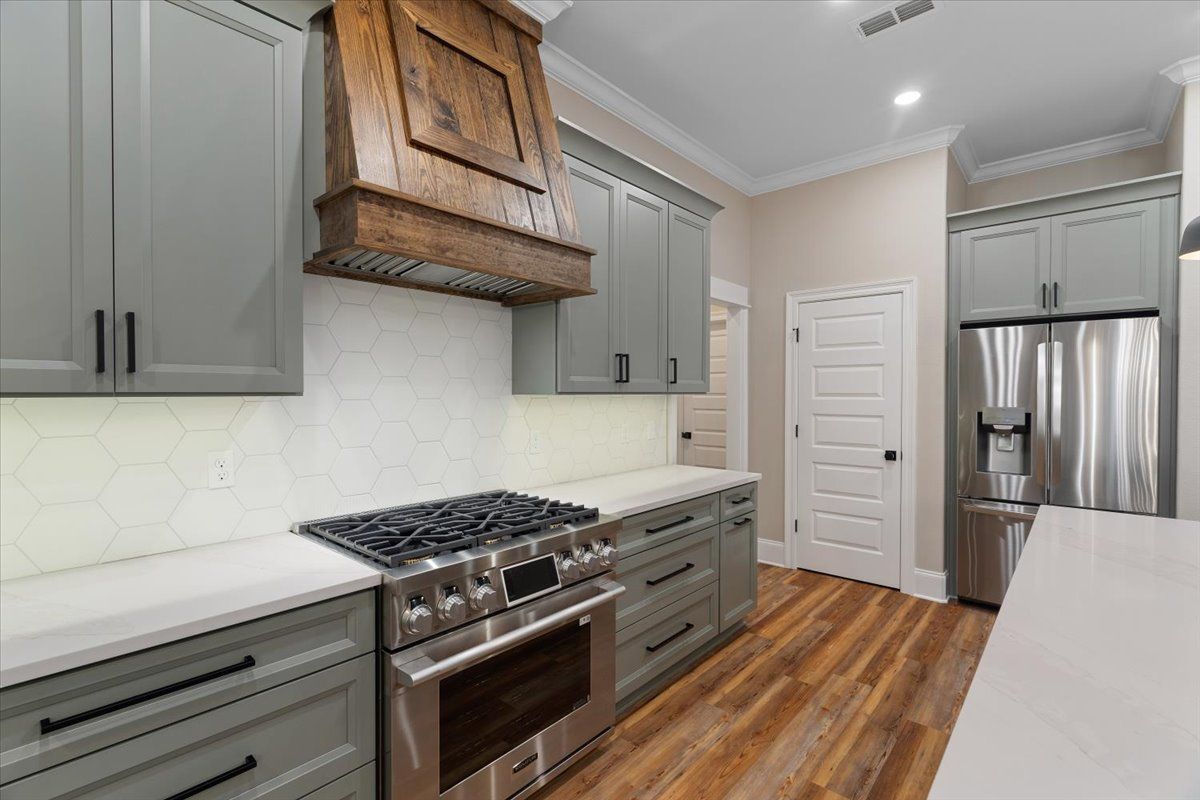 A kitchen with stainless steel appliances and gray cabinets.