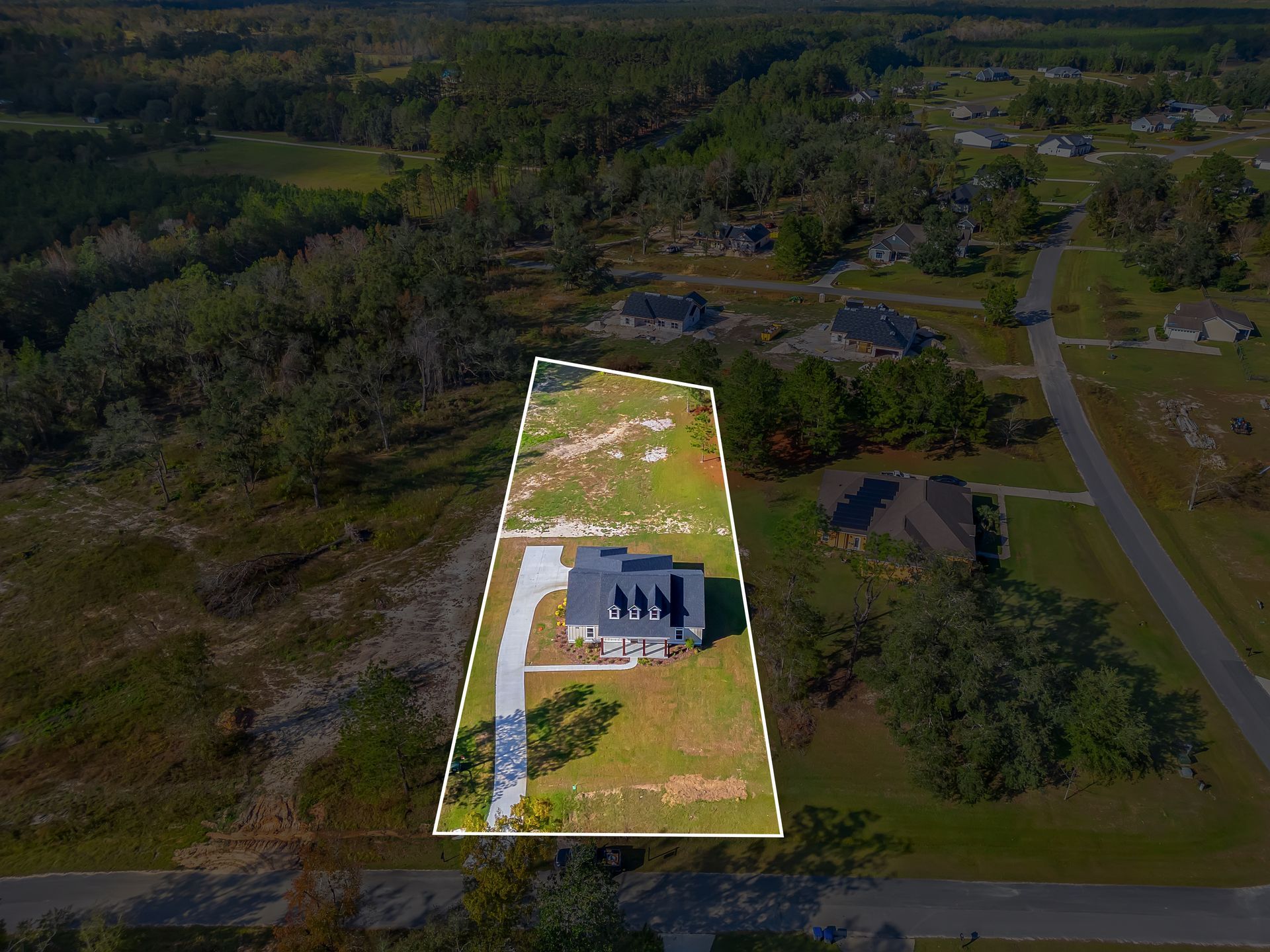 An aerial view of a house in a residential area surrounded by trees.