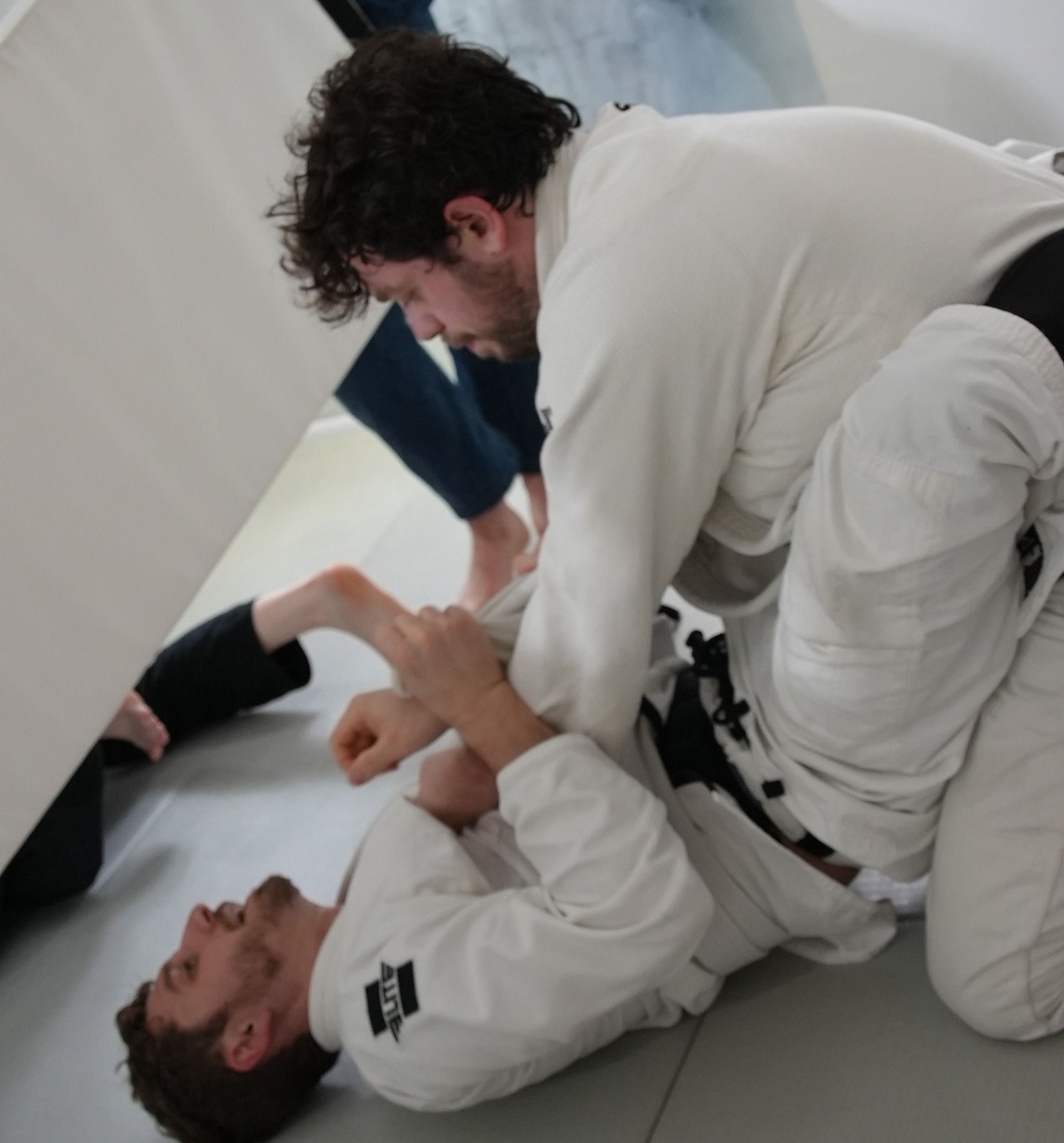 Adults practicing Brazilian Jiu-Jitsu sparring at Range Brazilian Jiu-Jitsu NYC in New York, NY for stress relief.