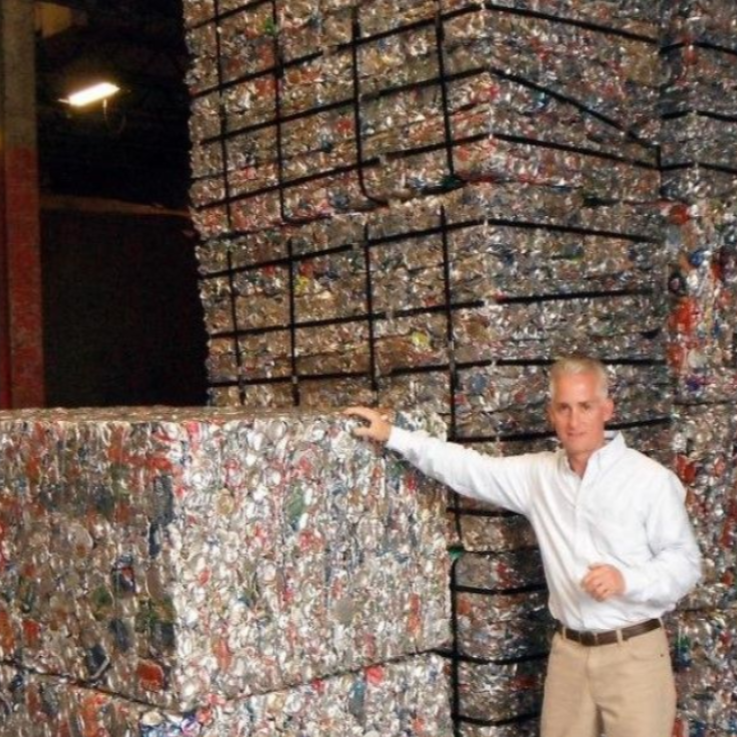 Two people on a boat at sunset, with one steering while the other stands nearby.