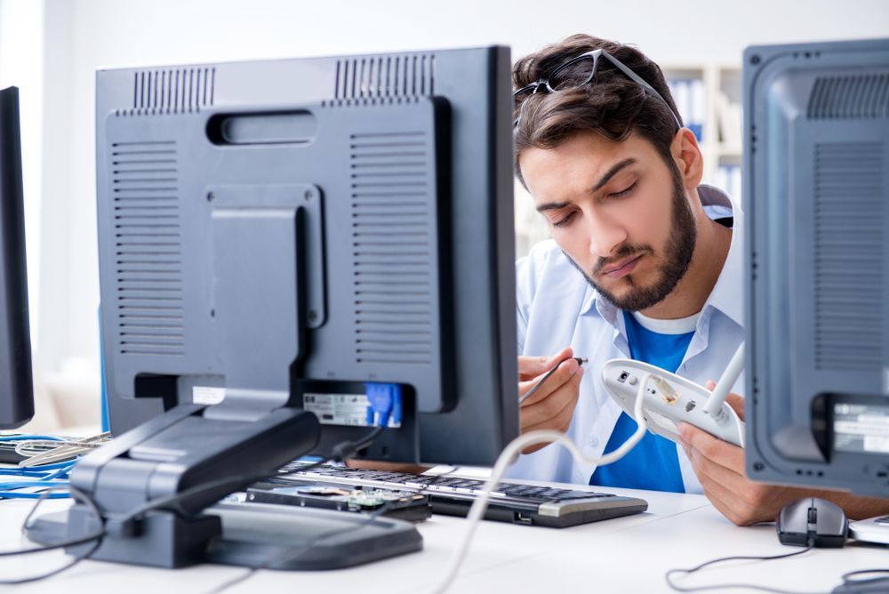 A Man is Working on a Computer in Front of Two Monitors — Complete Computing Consultancy In Childers, QLD