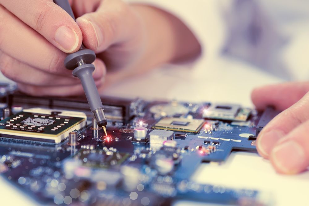 A Person is Working on a Motherboard With a Soldering Iron — Complete Computing Consultancy In Childers, QLD
