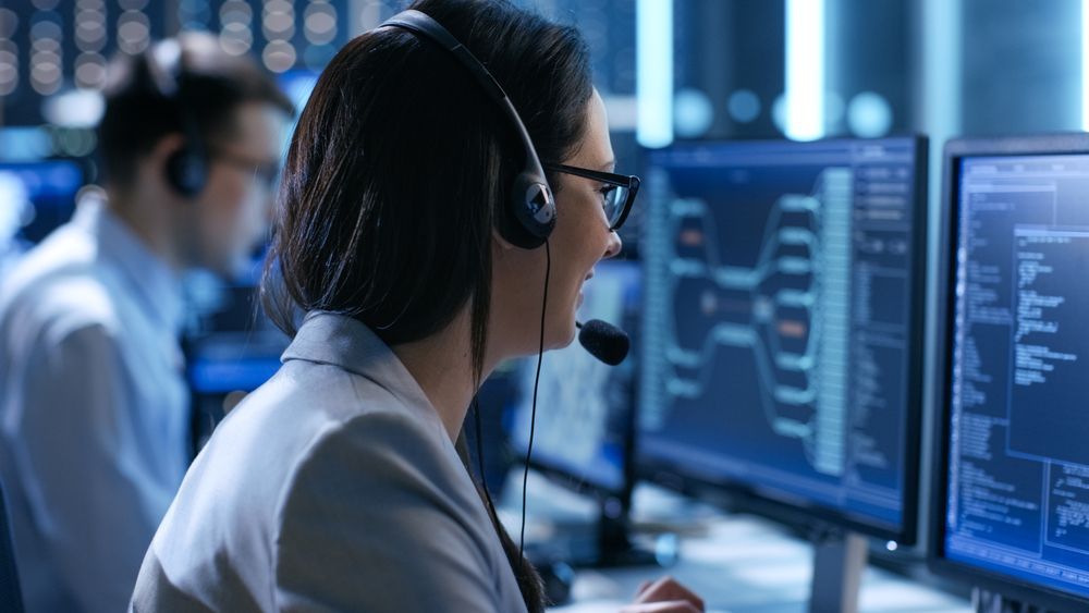 A Woman Wearing a Headset is Sitting in Front of a Computer — Complete Computing Consultancy In Rainbow Beach, QLD