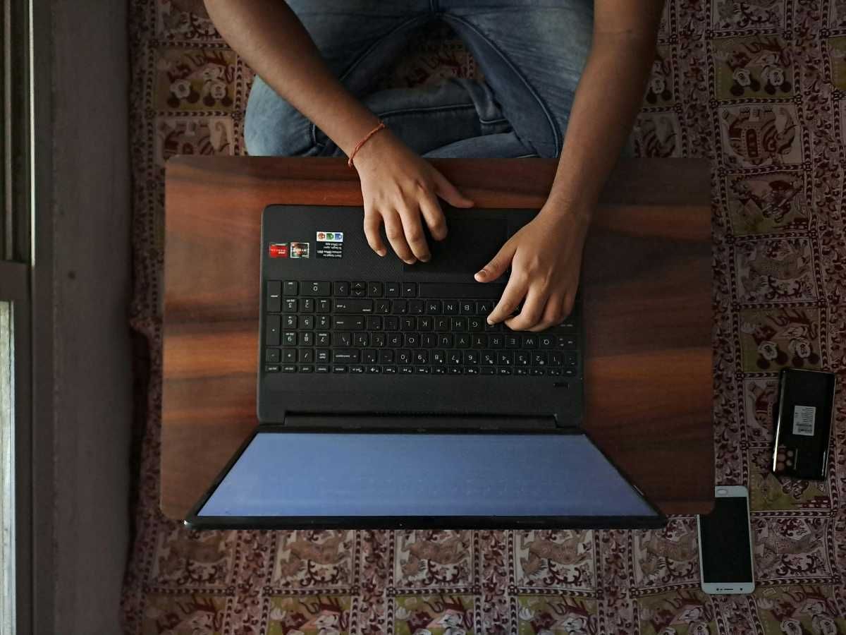 A Person is Using a Laptop Computer on a Wooden Table — Complete Computing Consultancy In Maryborough, QLD